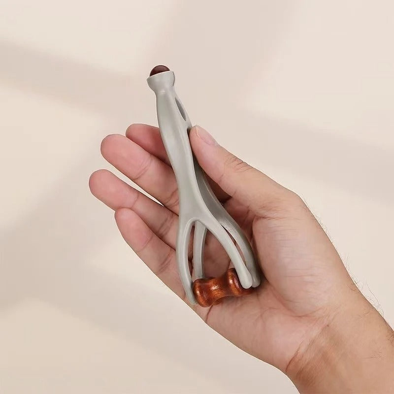 Hand holding gray and wood-handled massage tool for muscle relief and relaxation